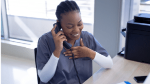 Une jeune secrétaire souriant lors de la gestion des patients au téléphone